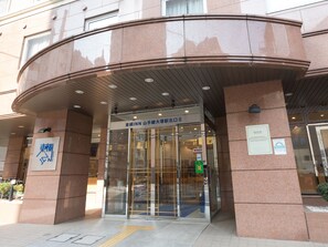 A hotel entrance with a curved facade, glass doors, and a sign indicating it is an Inn. - Toyoko Inn Tokyo Yamanote Line Otsuka Station Kita 2 (Tokyo)