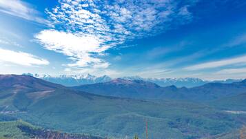 A mountainous landscape with a clear sky and distant snow-capped peaks.