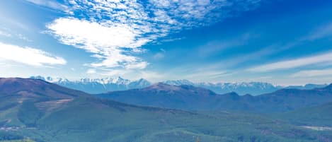 A mountainous landscape with a clear sky and distant snow-capped peaks.