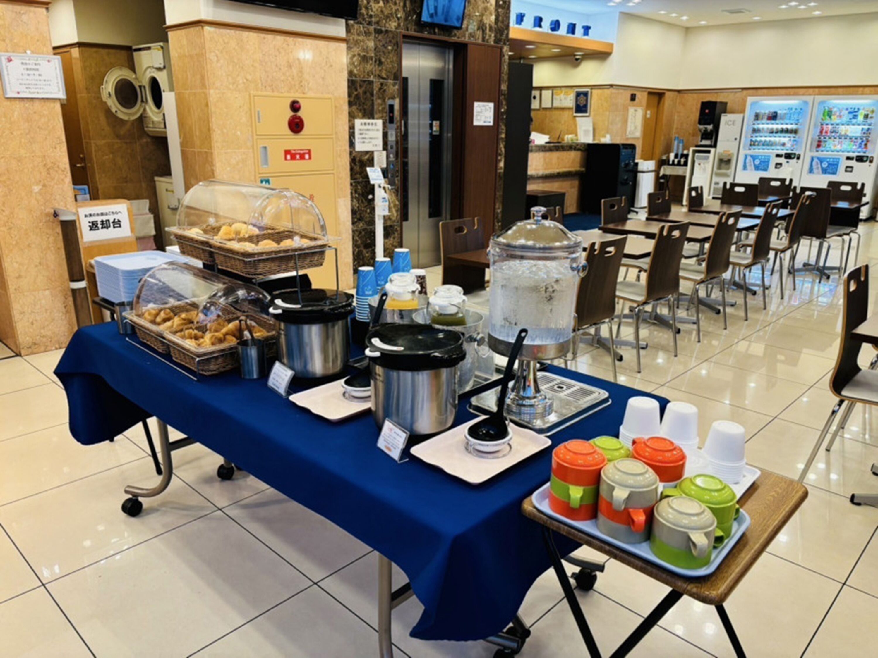 A buffet setup with various food items and beverages, a water dispenser, and a sign indicating the front area.