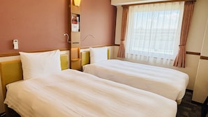 A hotel room with two beds, a bedside table, a lamp, a window with curtains, and a wall-mounted phone. - Toyoko Inn Sakudaira Station Asama (Saku)