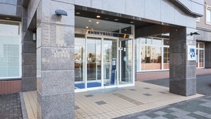 The entrance to a building with a stone facade, glass doors, and a sign indicating it is an Inn. - Toyoko Inn Chiba-minato Ekimae (Chiba)