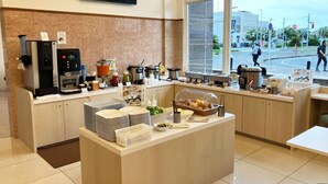 A modern breakfast area with a coffee station, food display, and a large window offering a view of the street. - Toyoko Inn Chiba-minato Ekimae (Chiba)