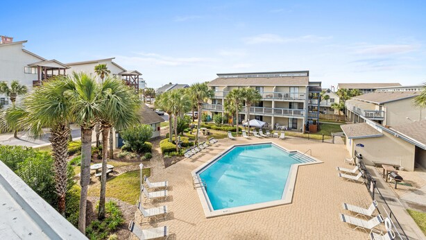 A hotel with a swimming pool, palm trees, and lounge chairs. - Sunswept Condo Rentals by Panhandle Getaways (Panama City Beach)