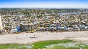 A coastal town with a beachfront hotel featuring multiple floors, a marina, and a bridge in the background. - Sunswept Condo Rentals by Panhandle Getaways (Panama City Beach)