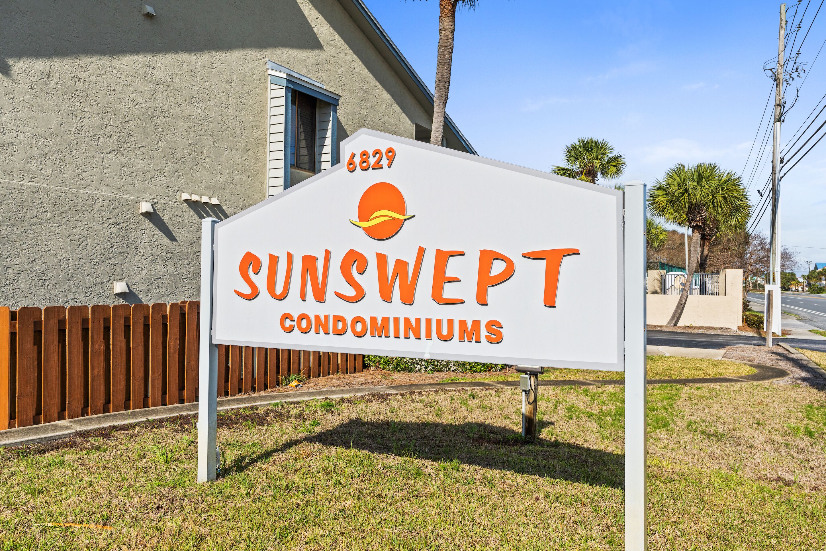 A sign for Sunswept Condominiums with a beach-themed logo.