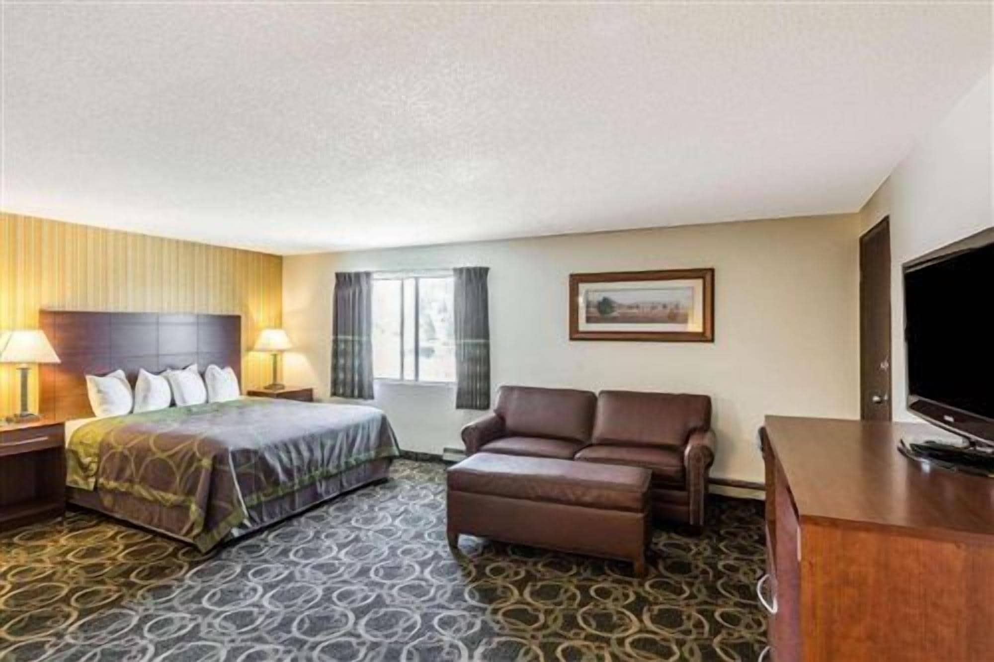 Ein Hotelzimmer mit Bett, Sofa, Fernseher und Schreibtisch.