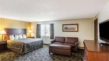 Ein Hotelzimmer mit Bett, Sofa, Fernseher und Schreibtisch.