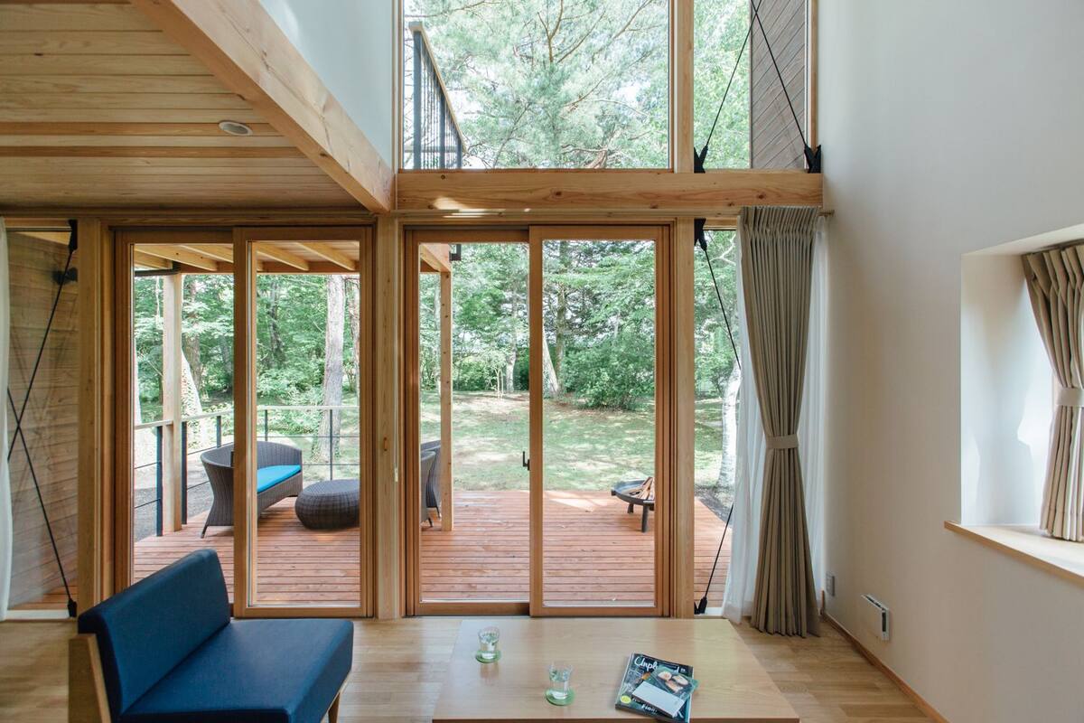 A modern interior with a wooden deck, a blue sofa, and a dining table.