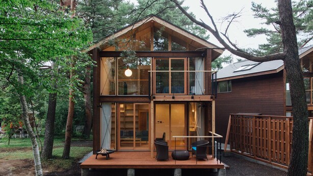A two-story wooden cabin with a deck, surrounded by trees. - Pica Yamanakako Village (Yamanakako)