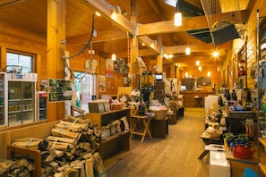 Un interior rústico de madera con una variedad de artículos expuestos, incluyendo leña, cestas y diversos productos envasados.