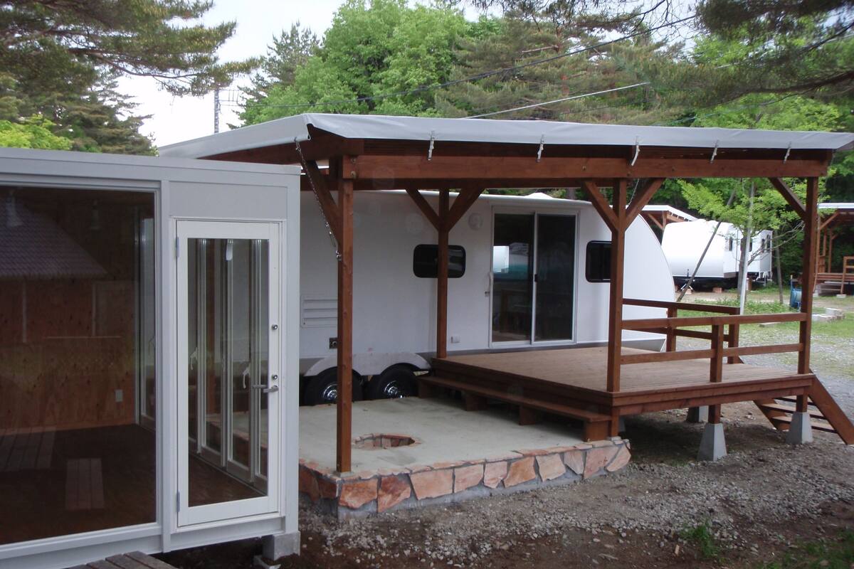 A mobile home with a covered porch, a sliding glass door, and a small outdoor seating area.