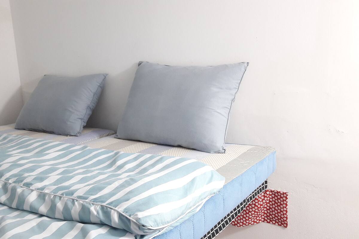 A bed with striped bedding and two pillows.