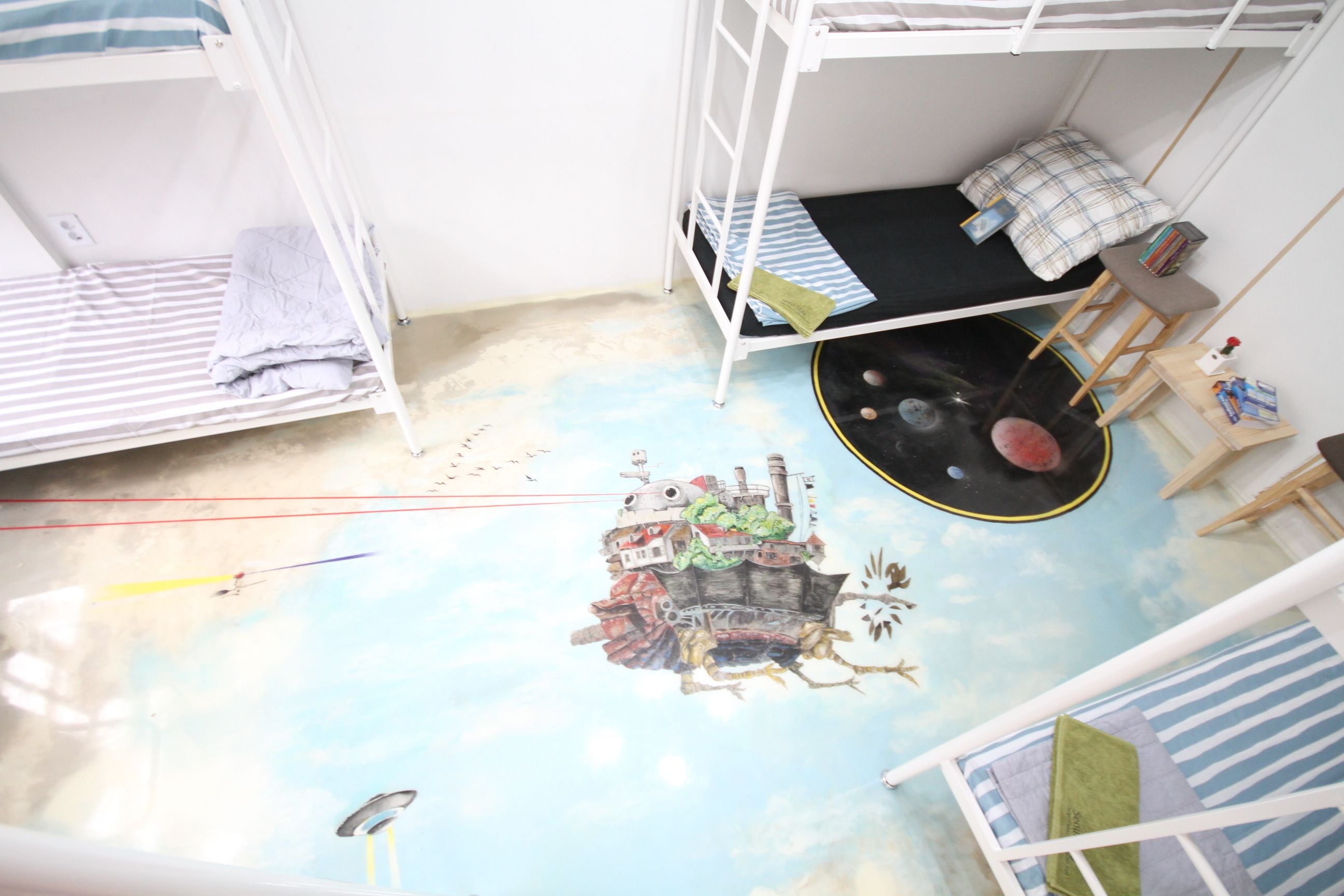 A bunk bed room with a mural of a floating city on the ceiling.