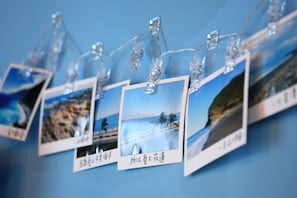 A wall with several framed photographs hanging on clips. - Ocean Lover Homestay (Hualien City)