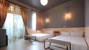 A room with two beds, a table, and a ceiling light fixture. - Ocean Lover Homestay (Hualien City)