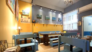 A restaurant interior with wooden benches, a long table, and wall-mounted paintings. - Ocean Lover Homestay (Hualien City)