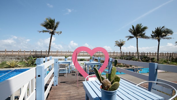 A wooden deck with a blue bench, a potted cactus, and a heart-shaped decoration. - Ocean Lover Homestay (Hualien City)