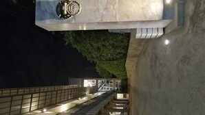 A multi-level parking structure with a central staircase and a decorative metal sign above. - The Loft Room Ubon (Ubon Ratchathani)