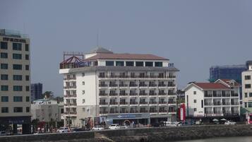 Um hotel com vários andares, varandas, vista para o rio e uma placa com 'UTOP UBLISS HOTEL'.