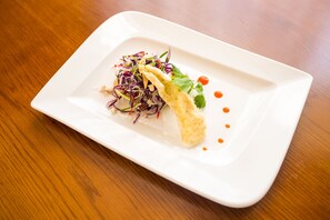 A white rectangular plate with a food dish on a wooden table.