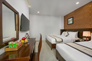 A hotel room with two beds, a desk with a basket of fruit, a mirror, and a television.