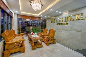 A hotel lobby with a reception desk, two wooden sofas, a chandelier, and a glass wall with the hotel name. - Bao Anh Boutique Hotel Da Nang (Da Nang)