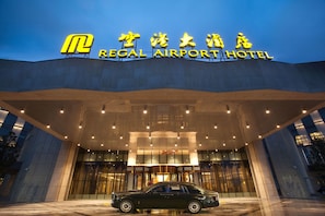 El exterior del Hotel Regal Airport, con un letrero llamativo y un coche clásico estacionado al frente.