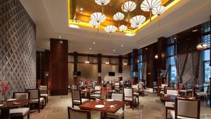 Un restaurante espacioso con varias mesas y sillas, faroles decorativos colgantes y un diseño de interiores moderno.