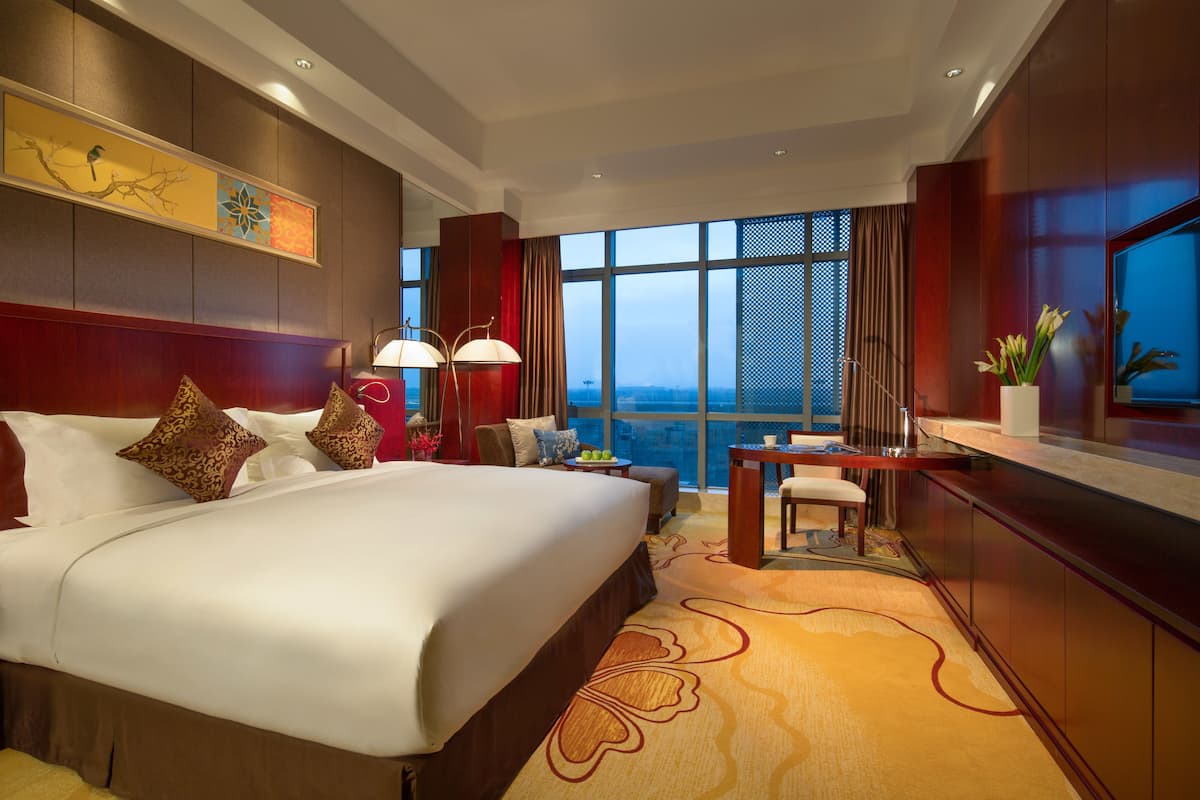 Habitación de hotel con una cama grande, un escritorio y vistas a la ciudad.