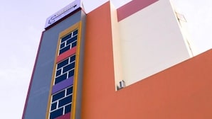 A multi-story building with a vertical stripe pattern on the facade, a flat roof, and a sign at the top. - Hotel Sakura Manado (Manado)
