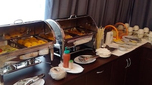 A buffet setup with various food items in glass containers, utensils, and condiments on a wooden counter. - Hotel Sakura Manado (Manado)