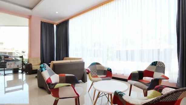 A modern living room with a sofa, two armchairs, and a small table. - Hotel Sakura Manado (Manado)