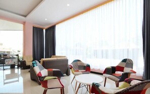 A modern living room with a sofa, two armchairs, and a small table. - Hotel Sakura Manado (Manado)