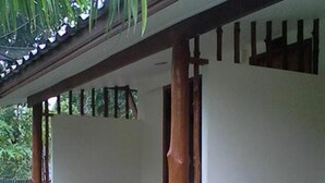 Une véranda couverte avec des balustrades en bois, des plantes en pot et un sol carrelé.