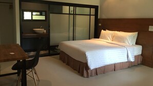 Une chambre d’hôtel avec un lit, un bureau, une chaise, un lavabo et un miroir.