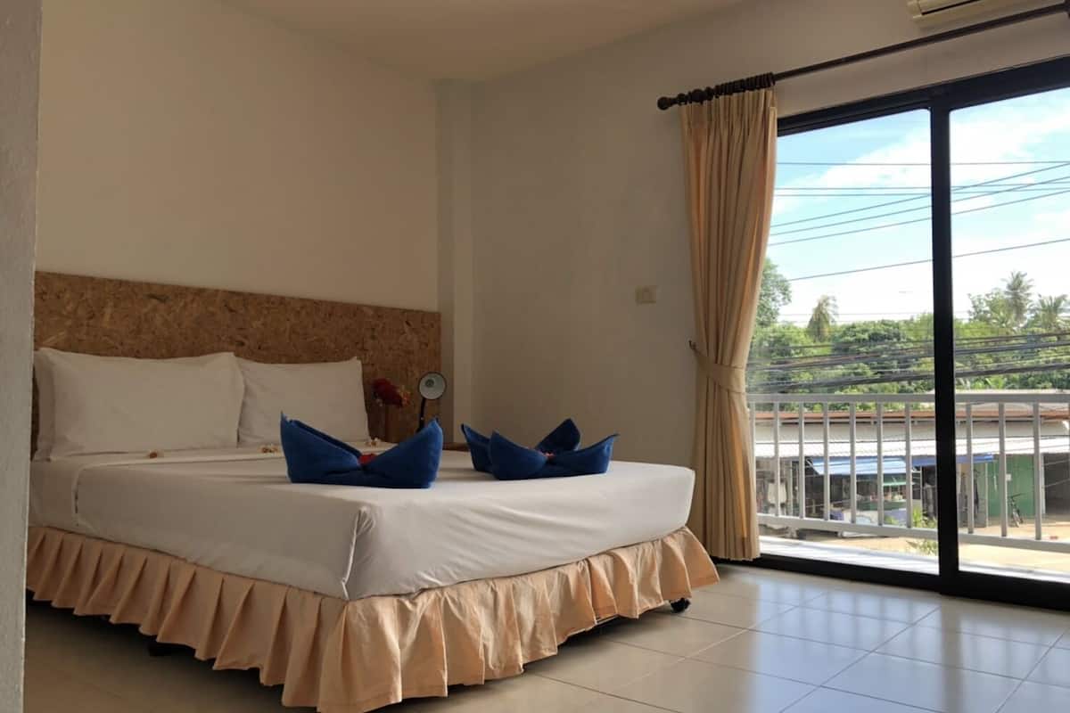 Ein Hotelzimmer mit einem großen Bett, einem Kopfteil, einem Fenster mit Vorhängen und Blick nach draußen.