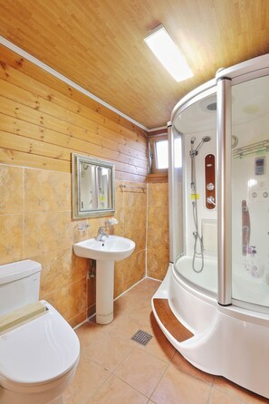 Een badkamer met een houten plafond, een wastafel, een toilet en een douchecabine.