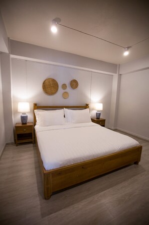A neatly arranged bedroom with a wooden bed, two bedside tables with lamps, and wall decor. - Vera Nidhra - Self check-in after 6pm (Bangkok)