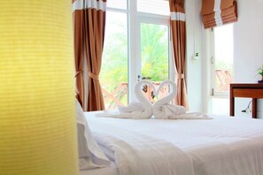 A hotel room with a bed, curtains, and a window with a view of greenery. - Thongsathit Hill Resort Khao Yai (Pak Chong)