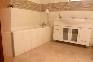 Un baño con bañera, tocador con lavamanos y armarios.