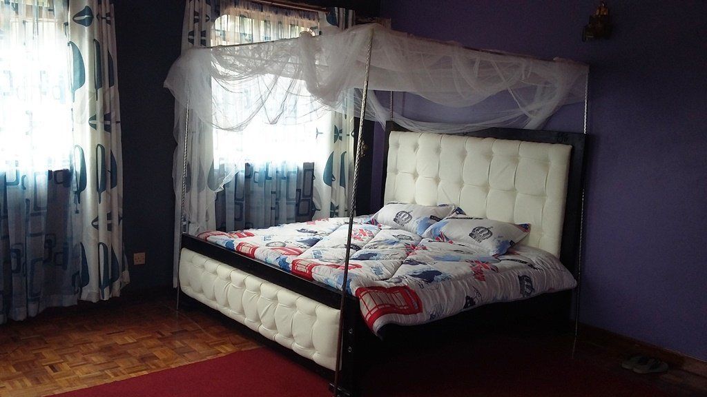 Ein Schlafzimmer mit Baldachinbett, rotem Teppich und gemusterten Vorhängen.
