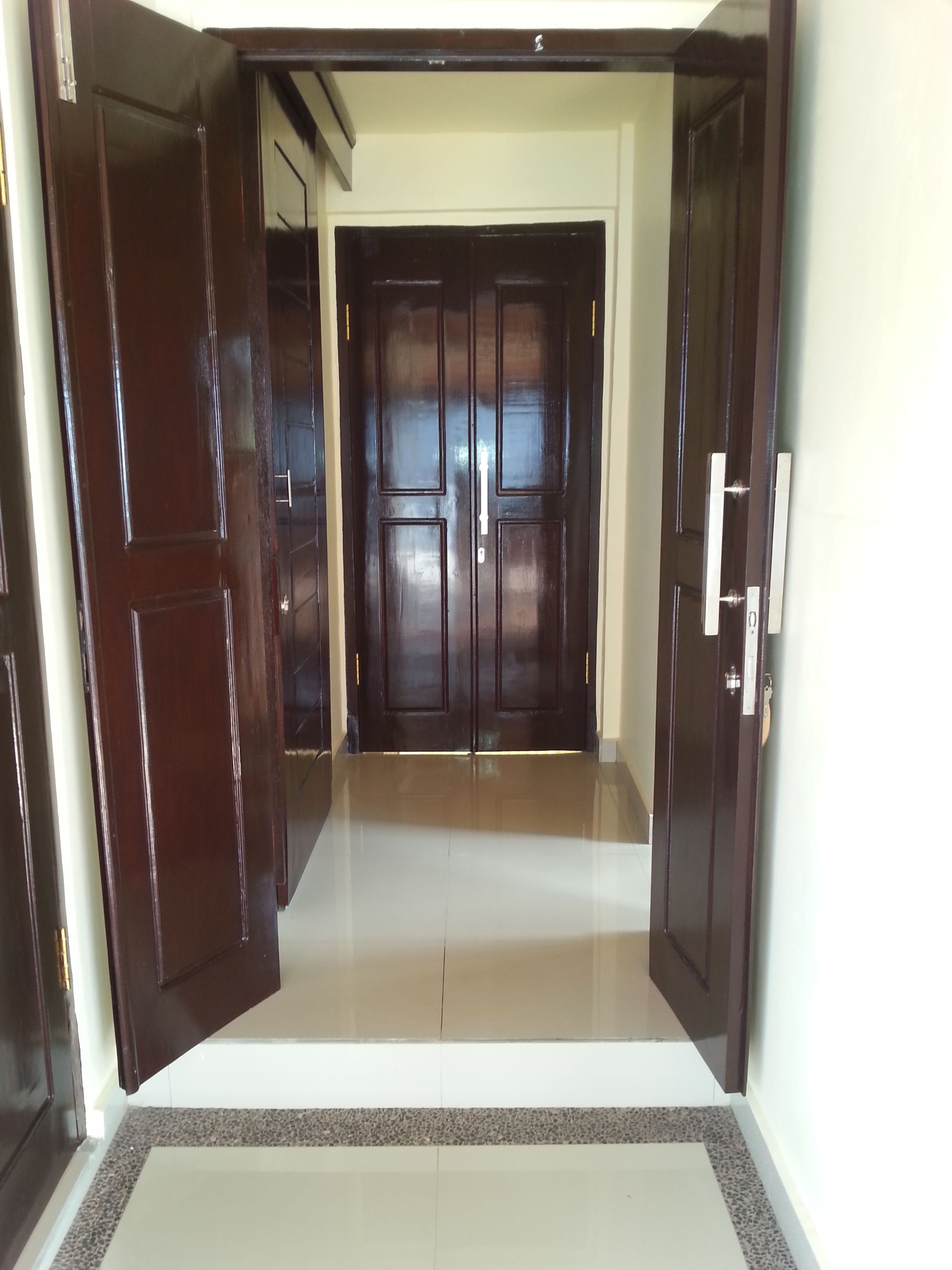A hallway with a double door at the end, leading to another room.