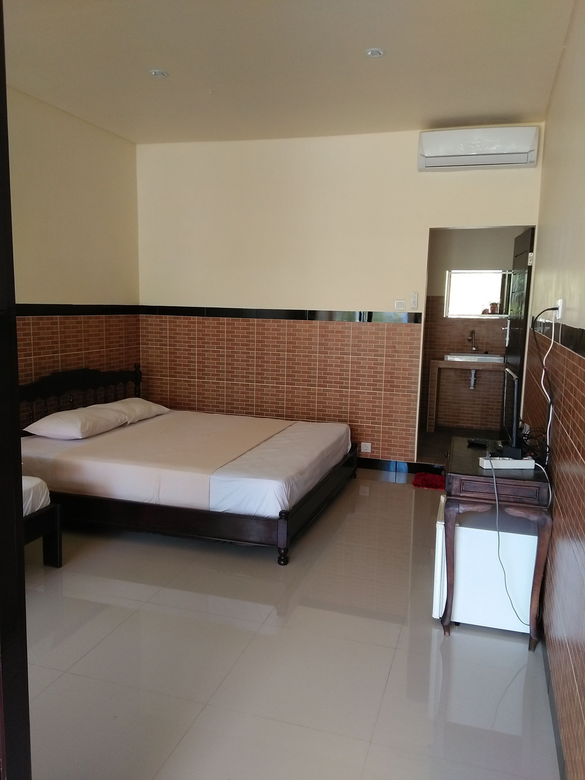 Un dormitorio con una cama, un baño pequeño con un lavabo y una ventana.