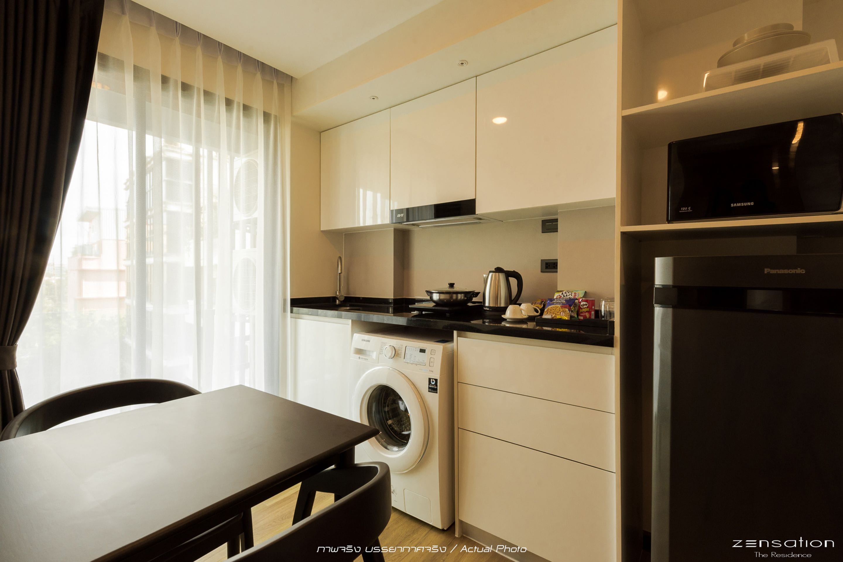 A compact kitchen with a washing machine, a microwave, and a refrigerator.