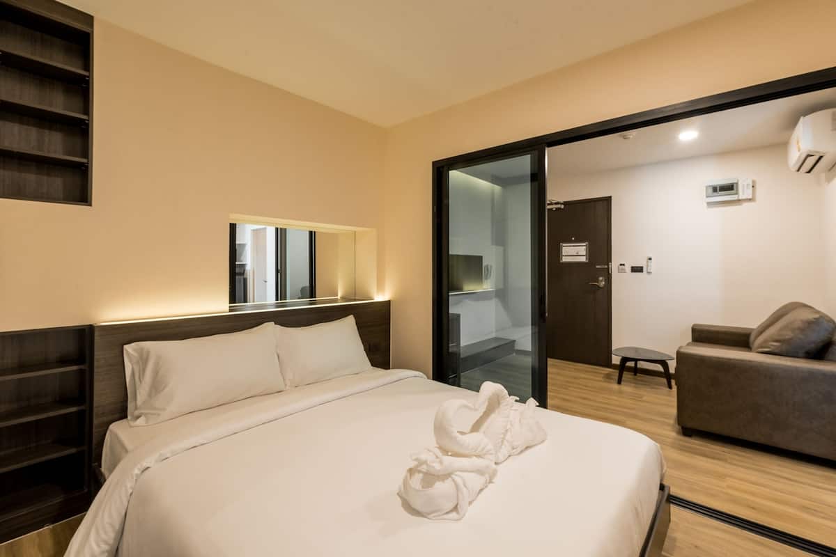 Une chambre d’hôtel avec un lit, un canapé, une petite table et un miroir.