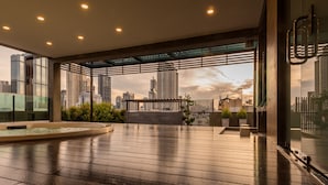 Una terraza moderna en la azotea con vista a la ciudad, una fuente circular y un pérgola.