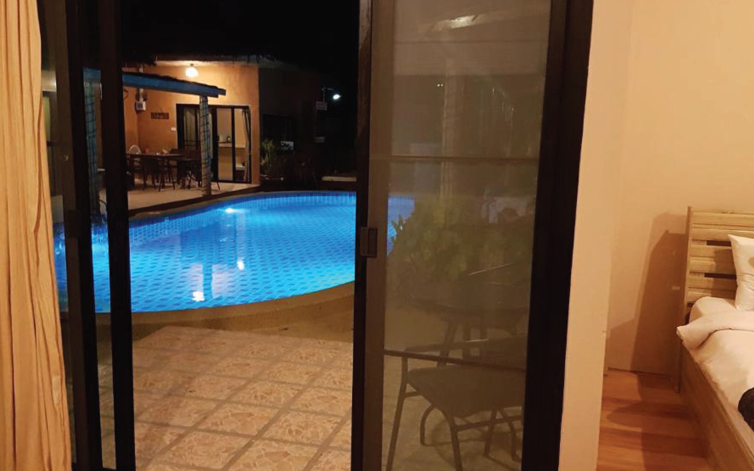 A room with a view of a swimming pool and a patio area.