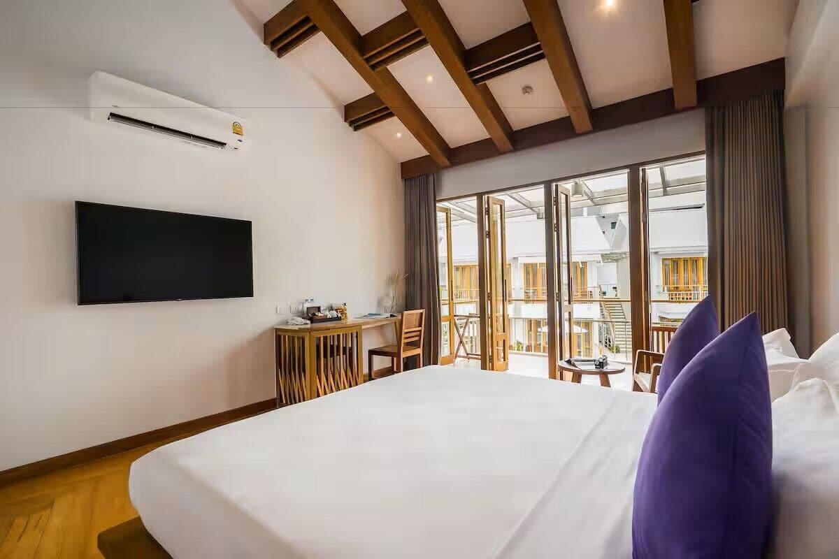 Una habitación de hotel con cama, televisor, escritorio y balcón con vistas.