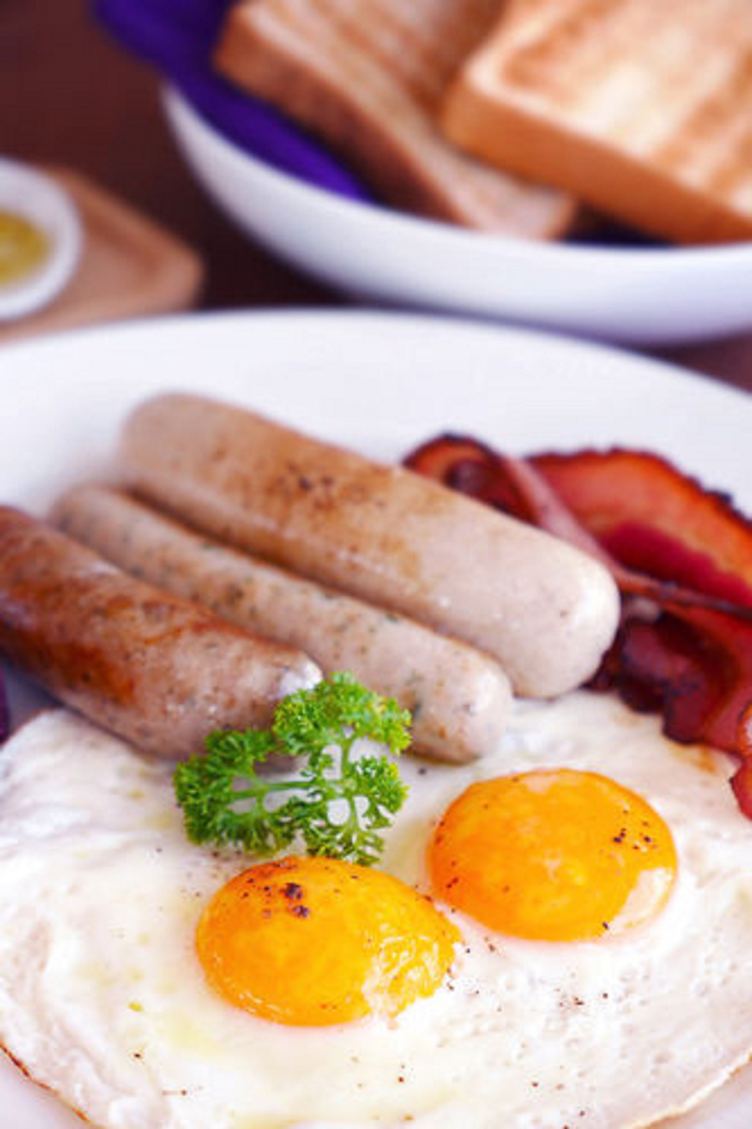A plate with sausages, bacon, and two fried eggs.